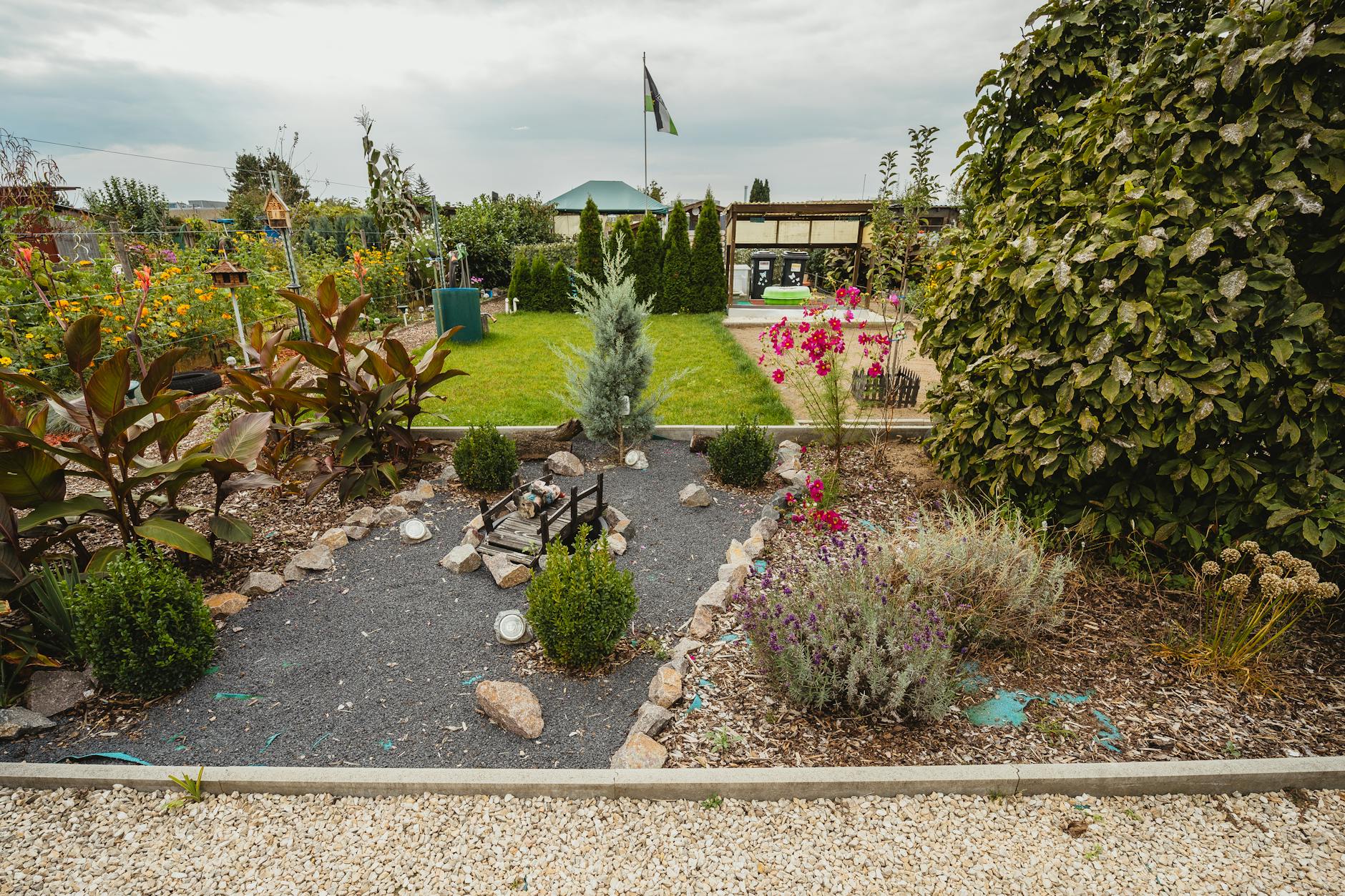 Explore a vibrant community garden featuring lush greenery, colorful flowers, and a quaint stone pathway.